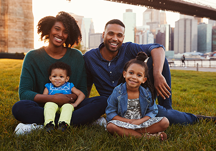 A happy African-American family smiles while sitting together in an urban park.